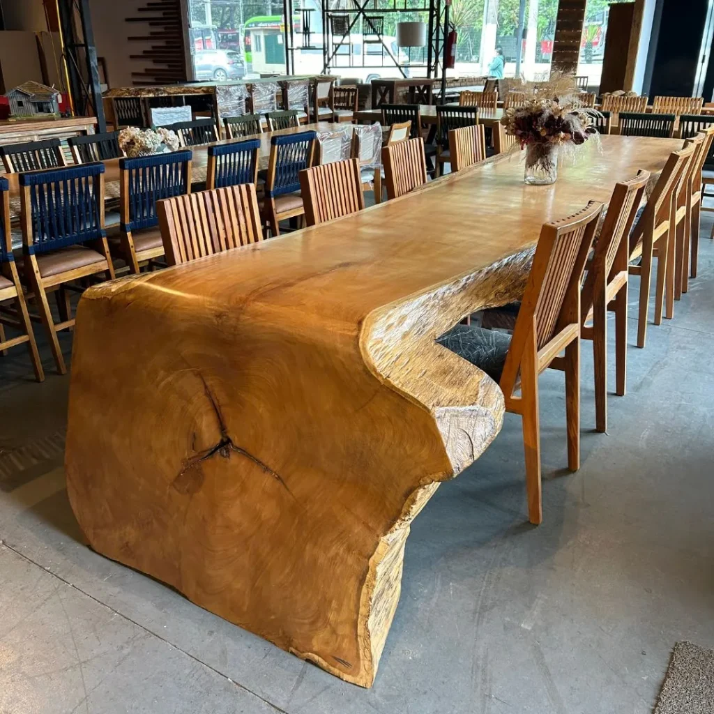 Mesa cascata de madeira maciça com lateral curva e cadeiras de madeira em showroom de Curitiba