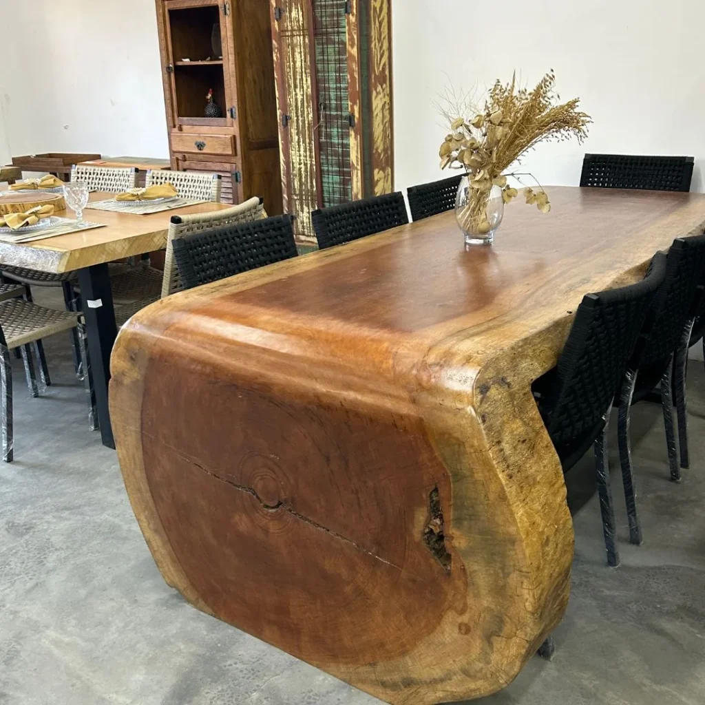Mesa cascata de madeira maciça com lateral arredondada e cadeiras pretas trançadas, em Curitiba