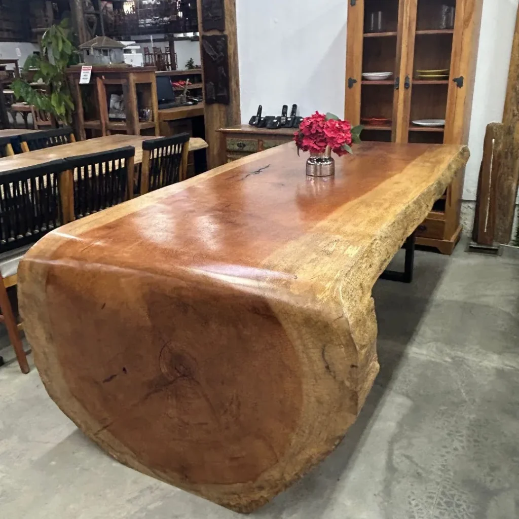Mesa cascata de prancha maciça com lateral curva e arranjo de flores, no showroom de Curitiba