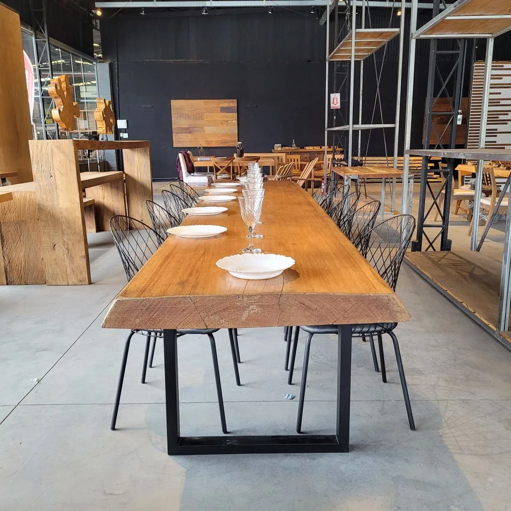 Mesa costaneira de madeira maciça com pé de ferro em U, posta para refeição no showroom em Curitiba